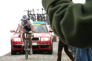 Un ciclista compitiendo en una carrera automovilística.