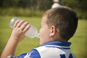 Niño toma un descanso del juego y bebe agua.