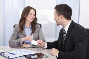 Businessman And Businesswoman Exchanging Visiting Card At Office Desk