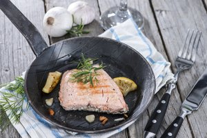 El salmón frito en una sartén con limón y hierbas