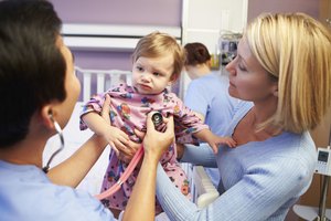 Un bebé y su madre en una sala de examen con un pediatra.