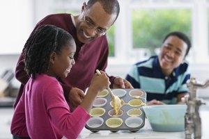 Un padre hornea muffin con sus dos hijos.