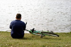 Un hombre sentado en el pasto frente al río