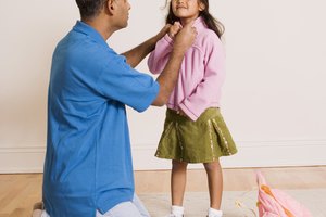 Father helping daughter put on jacket
