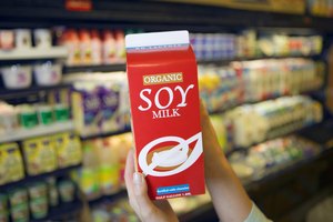 Una mujer sostiene un envase de leche de soya.