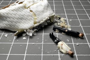 Two groom figurines lying at destroyed wedding cake on tiled floor