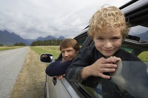 Boy (5-7 years) and father leaning out of car windows, smiling, portrait, close-up