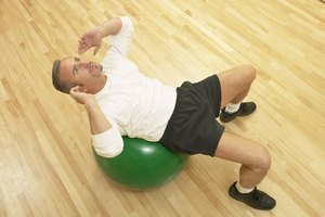 Un hombre hace abdominales (sit-ups) sobre un balón en el gimnasio.
