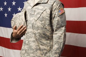 Soldier holding helmet by American flag