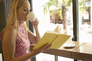 Una joven bebiendo una taza de café mientras lee