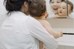 Jupiterimages/Creatas/Getty Images Around 12 months of age, a toddler develops self-awareness and recognizes her reflection in the mirror.