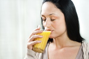 Mujer bebiendo un vaso de jugo de naranja.