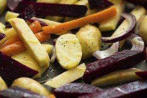 Verduras asadas rociadas con aceite de oliva en una bandeja para hornear.