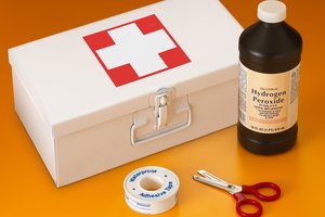Botiquín de primeros auxilios con agua oxigenada, tijeras y esparadrapo.
