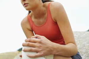 Siéntate con tu pierna lesionada extendida delante de tí. Utiliza los dedos índice y pulgar de ambas manos para ejercer presión y mover la rótula hacia abajo, hacia la espinilla.