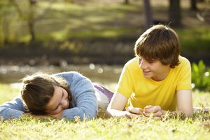 Teenage boy and girl (13-15) lying on grass, smiling