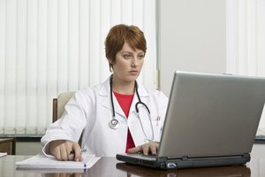 Doctor que mira la computadora portátil.