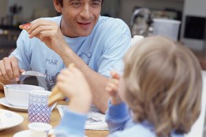 Father having breakfast with son (4-6) smiling