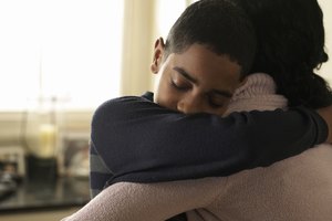 Boy (12-13) hugging mother at home