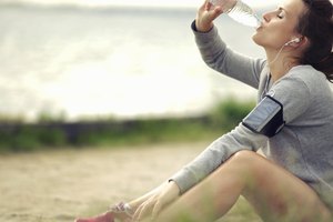 La mujer bebe agua embotellada después de correr en el camino.