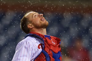 El receptor de los Filis Erik Kratz trata de atrapar una bola alta en la lluvia en un juego de 2013.
