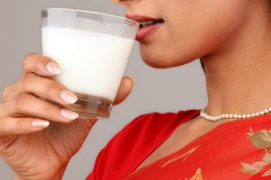 Una mujer tomando una taza de yogurt.