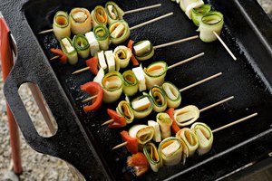 Las brochetas coloridas de verduras con tofu en una parrilla.