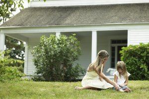 Young woman playing with daughter (4-5) on lawn outside house