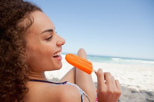 Mujer en la playa comiendo un helado.