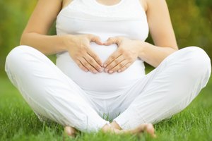 Mujer embarazada formando un corazón sobre su vientre.