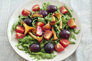 Una ensalada de rúcula con champiñones y tomates.