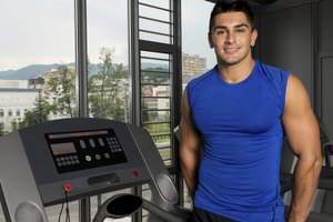 Hombre de pie al lado de la cinta en el gimnasio.