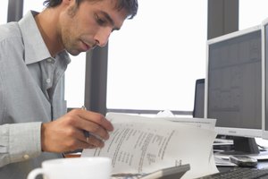 Businessman using PCs and looking at documents, close up, side view