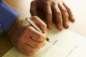 Close-up of man's hands signing house deeds with pen