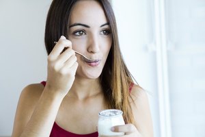 Una mujer comiendo un yogur.