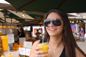 Una mujer bebiendo un vaso de jugo de naranja en un café.
