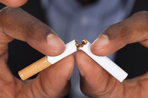 Imagen de las manos de un hombre rompiendo un cigarrillo