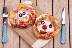 Dos mini pizzas inglesas de muffin con caras.
