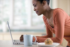 Una mujer registra sus opciones de alimentos en una computadora portátil en la cocina.
