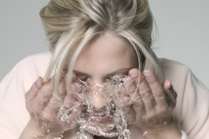 Una mujer salpica agua en su rostro.