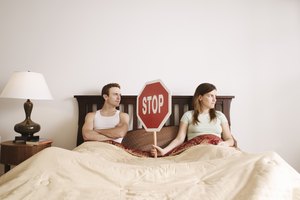 Couple holding stop sign in bed