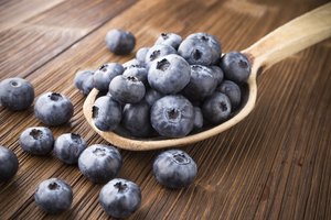 Cuchara llena de moras azules (blueberries).