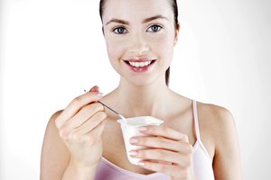 Una chica comiendo de un pote de yogurt