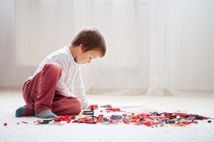 Little child playing with lots of colorful plastic blocks indoor