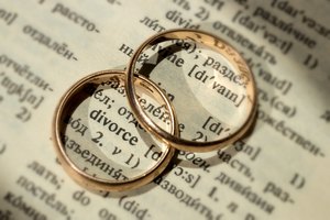 Two separate wedding rings next to the word 'divorce'. The concept of divorce, parting, infidelity . Selective focus.
