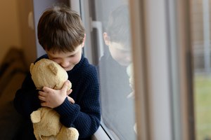 Sad boy is hugging his teddy bear.