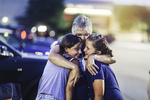 grandmother hugging two of her granddaughters at night during Independence Day celebration