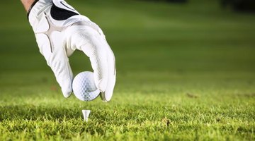 Close-up of a hand placing a golf ball on a tee