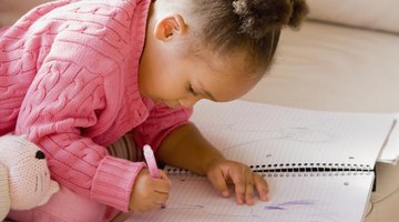 Preschooler coloring in notebook.