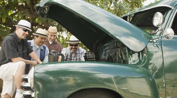 Group of men looking at engine of restored classic vehicle